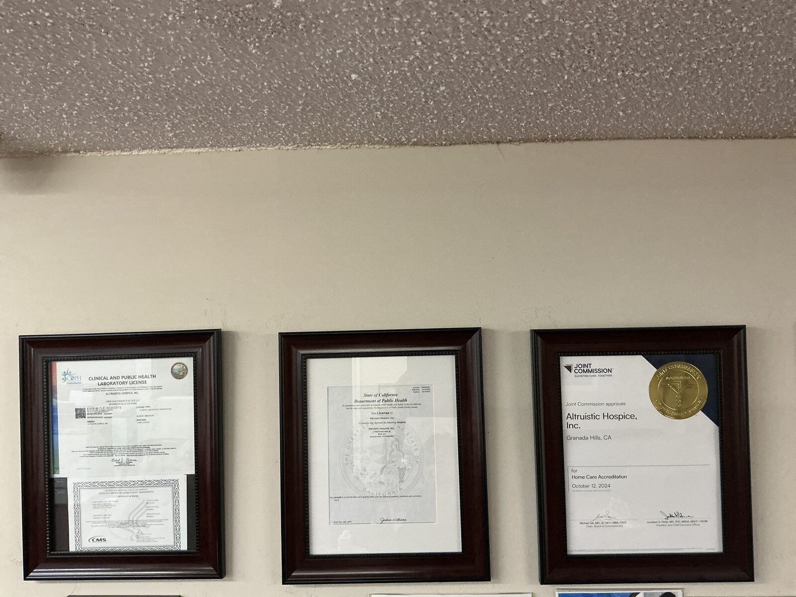Altruistic Hospice, Inc.'s California license and Joint Commission accreditation certificates, displayed in the Granada Hills office